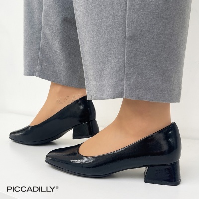 Sapatos pretos de salto médio com acabamento brilhante e calças cinzentas