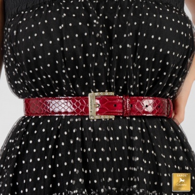 Cinto vermelho texturado com fivela dourada num vestido preto às bolinhas brancas