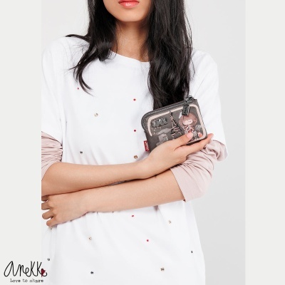 Carteira pequena em tecido com padrão gráfico castanho-avermelhado segurada por mulher com camisola branca e mangas cor de rosa