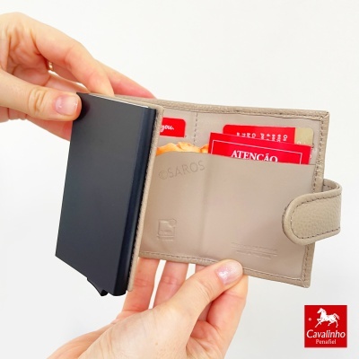 Carteira bege em couro com cartões vermelhos e compartimento preto, segurada por mãos femininas
