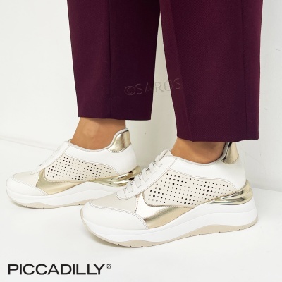 Ténis brancos com detalhes dourados metálicos e sola branca usados com calças vinho