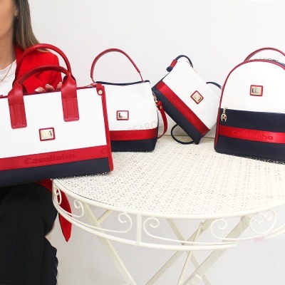 Quatro malas femininas Cavalinho em branco, vermelho e azul marinho sobre mesa branca