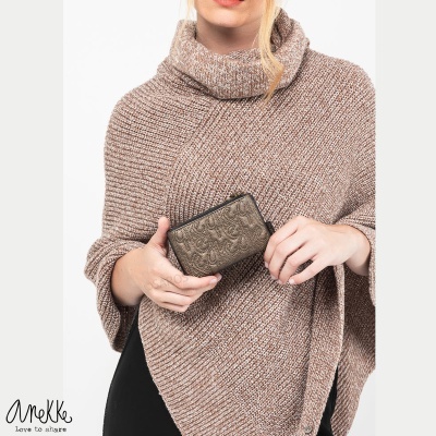 Pessoa com capa de malha castanha segurando carteira metálica com padrão em relevo