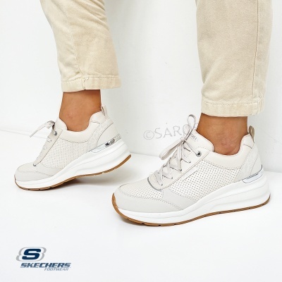 Ténis Skechers bege claro com sola branca e castanha usados com calças bege