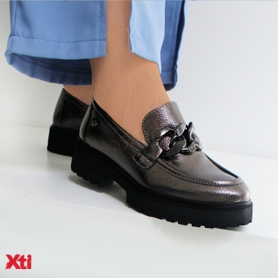 Sapatos mocassins metalizados prateados com corrente preta e sola grossa preta.