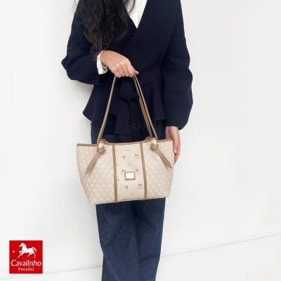 Mala feminina bege matelassê com detalhes castanhos e padrão Cavalinho segurada