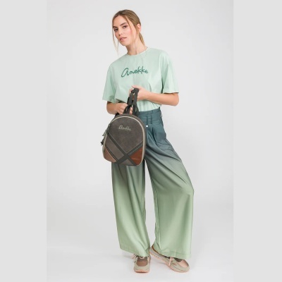 Mulher com t-shirt verde clara Anekke, calças largas verde degradê e mochila marrom Anekke
