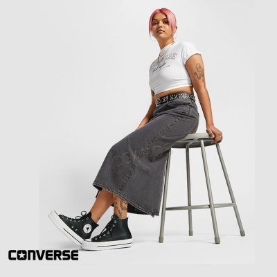 Mulher sentada com tênis Converse pretos e roupa casual