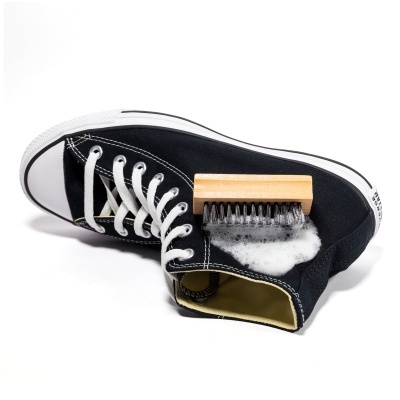 Tênis preto a ser limpo com escova e espuma