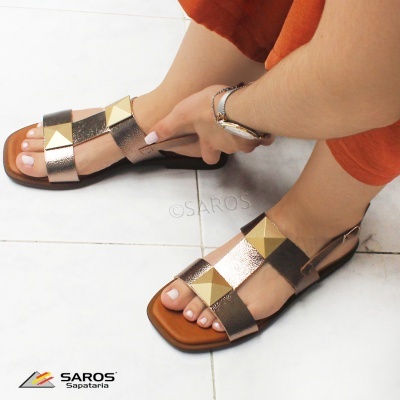 Sandálias femininas douradas e prateadas com tachas grandes, em piso branco