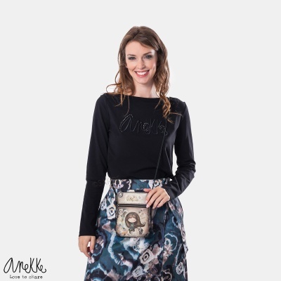 Mulher sorridente com blusa preta Anekke e bolsa pequena estampada com boneca