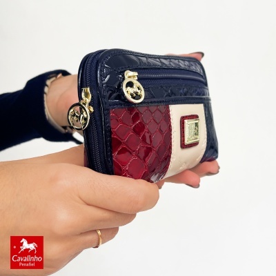 Carteira Cavalinho Penafiel azul, vermelho e branco com fechos dourados e textura tipo pele de crocodilo.