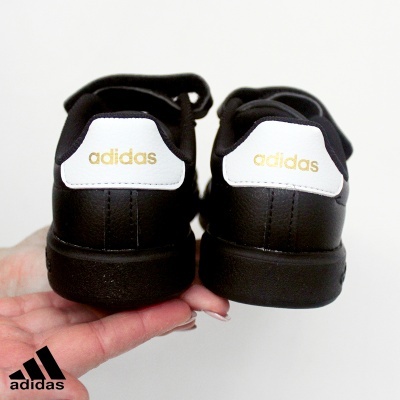 Sapatilhas Adidas pretas com parte traseira branca e logo dourado