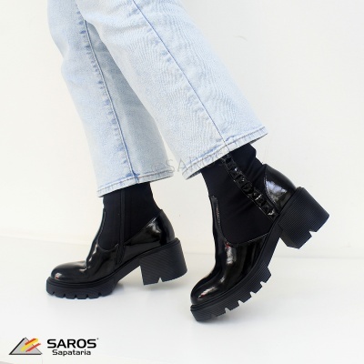 Sapatos pretos de salto grosso com sola dentada e calças de ganga claras