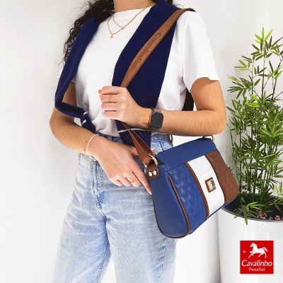 Mala azul, castanha e branca Cavalinho com padrão acolchoado e mulher com t-shirt branca e jeans
