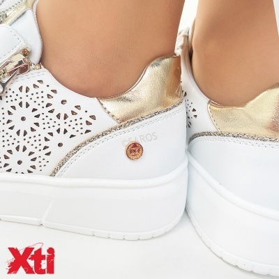 Ténis brancos com detalhes metálicos dourados e padrão de recortes florais