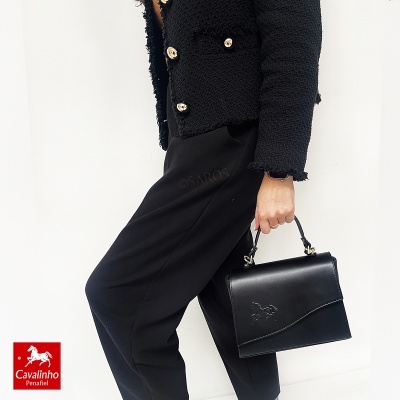 Bolsa preta de mão em pele com relevo de cavalo, casaco preto texturizado e calças pretas