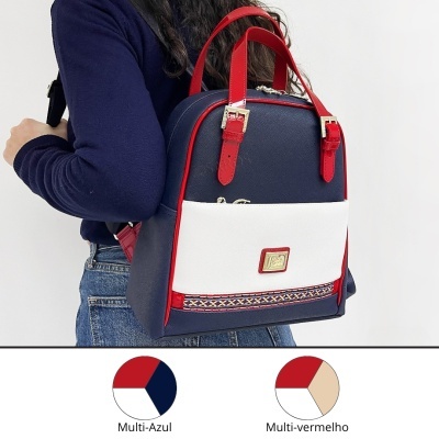Mochila azul, branca e vermelha com fivelas douradas, usada por pessoa com camisa azul e jeans