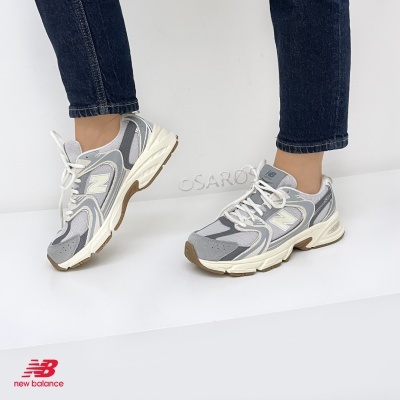 Ténis New Balance 820 cinza e branco com sola castanha em uso