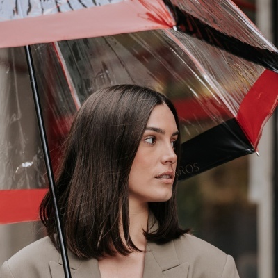 Mulher com guarda-chuva transparente com bordas vermelhas e pretas
