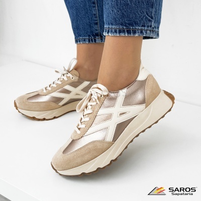 Tênis bege e prateado usados com jeans em fundo branco