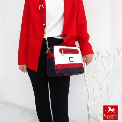 Mala feminina tricolor com fecho dourado usada por mulher com blazer vermelho