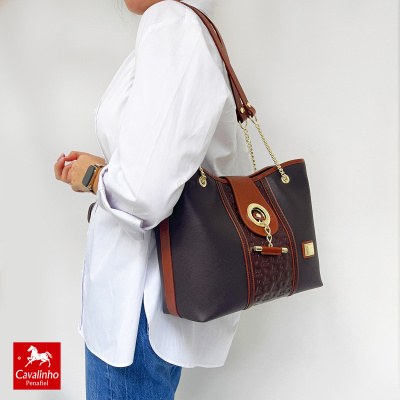Mulher com mala Cavalinho Penafiel castanha, camisa branca e jeans azuis