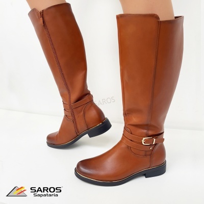 Bota castanha em pele com fivela dourada e fecho lateral sobre fundo branco