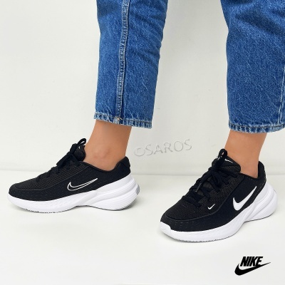 Ténis Nike pretos com sola branca usados com calças de ganga azul