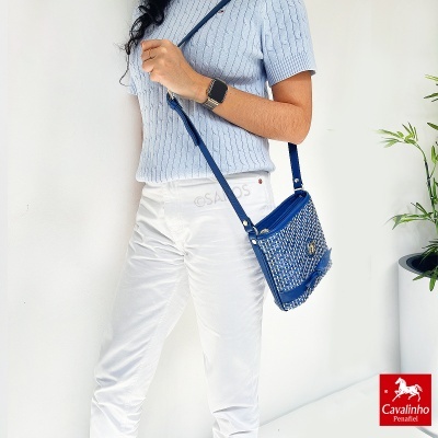Mulher com mala de ombro azul trançada e roupa azul clara e branca