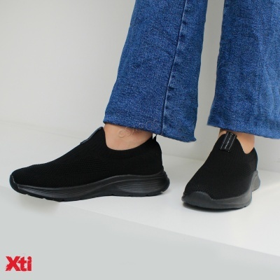 Sapatos slip-on pretos com sola preta usados com calças de ganga azuis