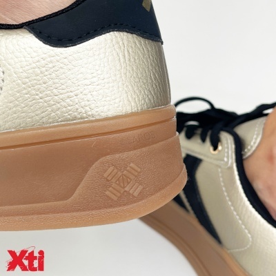 Ténis brancos e pretos com sola castanha e logo Xti vermelho