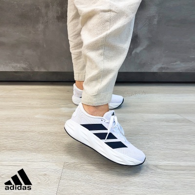 Ténis Adidas brancos com riscas negras e calças bege claro
