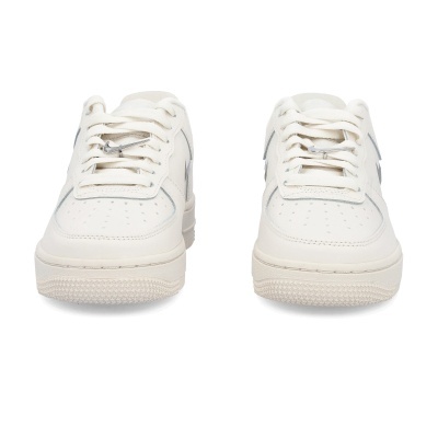 Par de sapatilhas brancas com detalhes cinza e um logo metálico da Nike nos atacadores