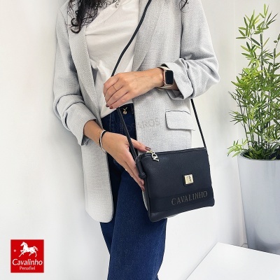 Mala preta Cavalinho em textura lisa com fecho dourado, usada com blazer cinzento e jeans