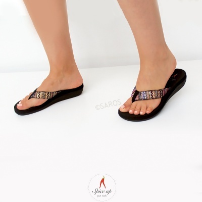 Chinelos pretos com tiras brilhantes multicoloridas em pés femininos sobre fundo branco