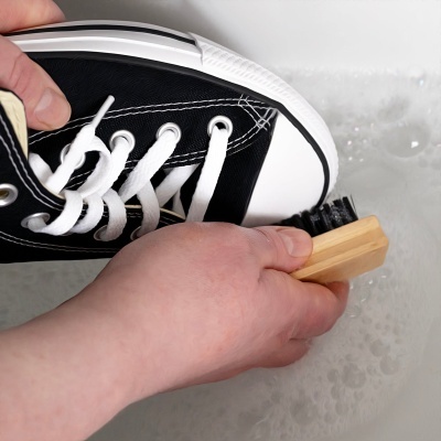 Sapato desportivo a ser limpo com escova e espuma.