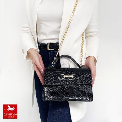Mala preta com padrão de pele de crocodilo e alça dourada em modelo