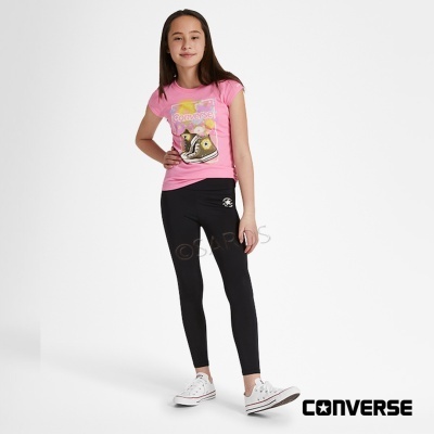 Menina a vestir t-shirt rosa, leggings pretas da Converse e sapatilhas brancas