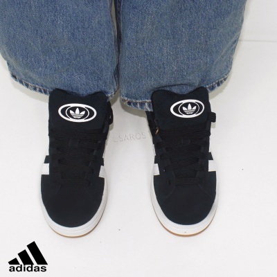 Sapatilhas Adidas pretas com sola branca e logótipo em calças de ganga