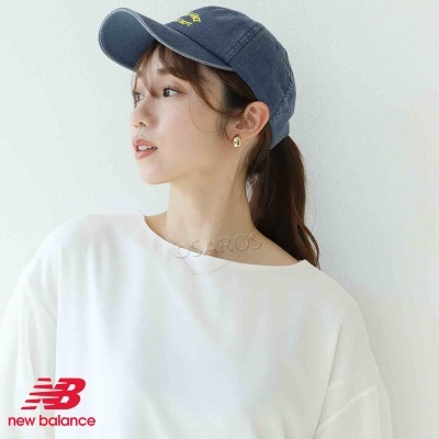 Mulher com boné azul escuro, t-shirt branca e brincos dourados