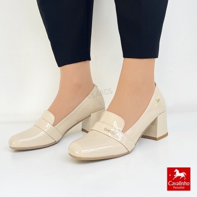 Sapatos de senhora bege claro em verniz com salto médio e faixa decorativa.