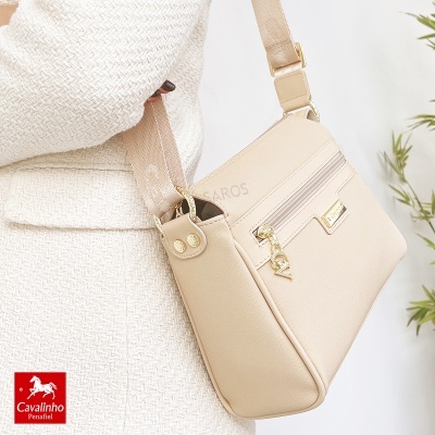 Mala bege com fecho dourado e alça larga, usada com casaco creme de malha