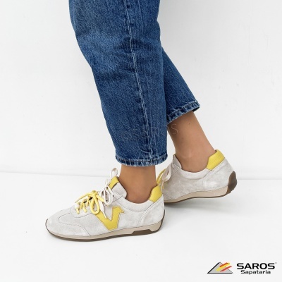 Sapatilhas brancas com detalhes amarelos e jeans azuis.