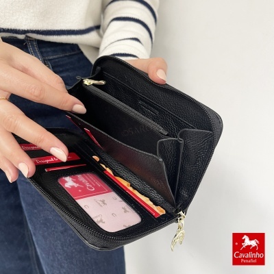 Carteira preta em pele com vários compartimentos interior exibida pela mão de mulher.