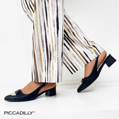 Sapatos preto de salto médio com detalhe dourado e calças de riscas verticais em tons neutros