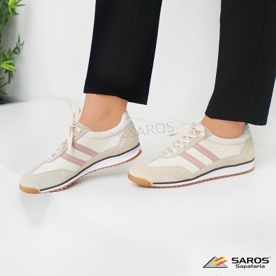 Sapatos desportivos bege com riscas cor-de-rosa e sola castanha usados com calças pretas