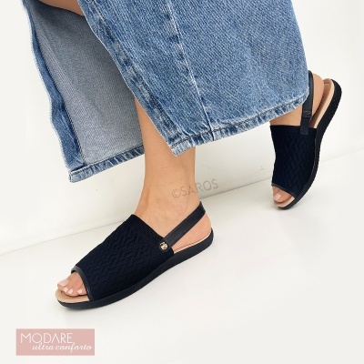 Sandálias Modare pretas com textura geométrica e tira no calcanhar usadas com jeans