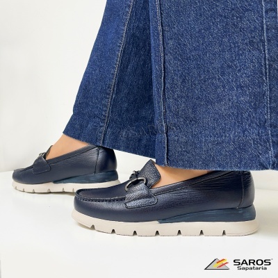 Sapatos mocassins pretos em pele usados com calças de ganga azul.