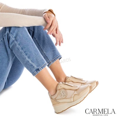 Sapatilhas bege claro em mulher sentada com jeans azul claro e camisola bege